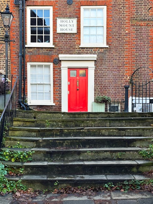 The image shows the front entrance of a residential property with a staircase leading up to two white front doors, each with decorative glass panels. The steps and landing are tiled in a black and bei